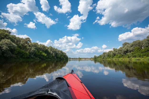 Flottant le long d'une grande rivière calme avec des nuages duveteux dans le ciel