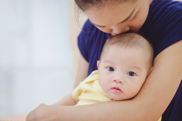 Flou artistique à la mère asiatique tenant et embrassant son bébé