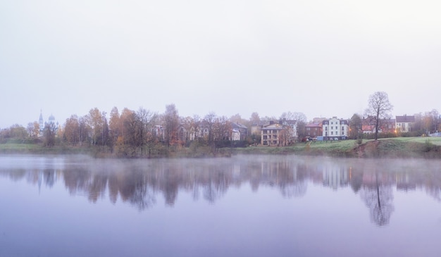 Flou artistique. Le village est dans le brouillard. Brume matinale sur la surface du lac près de la ville de Gatchina, en Russie. Vue panoramique.