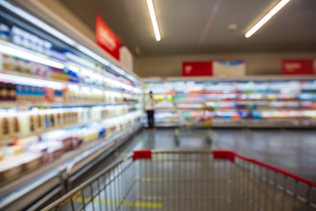 Le flou défocalisé de la boisson féminine des aliments laitiers achetant un panier d'achat mis sur une étagère à la boisson du supermarché.