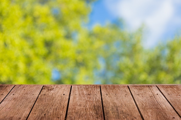 Flou fond d'arbre vert avec table en bois au premier plan pour la présentation du produit