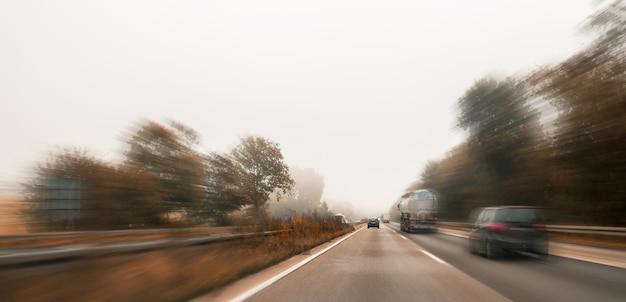 Flou de mouvement voitures de route à l'automne avec brouillard