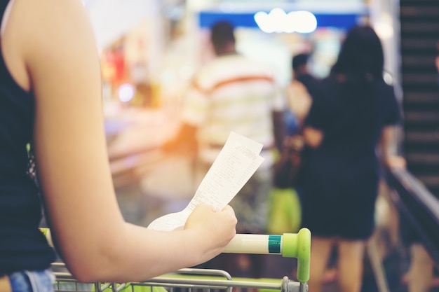 floue de la main de la femme tenir un projet de loi et une longue réception de supermarché