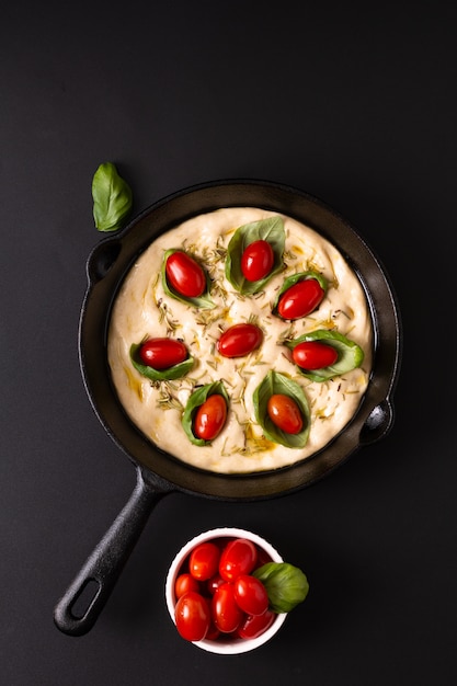 Focaccia bio fait maison dans une poêle en fonte sur fond noir avec espace de copie