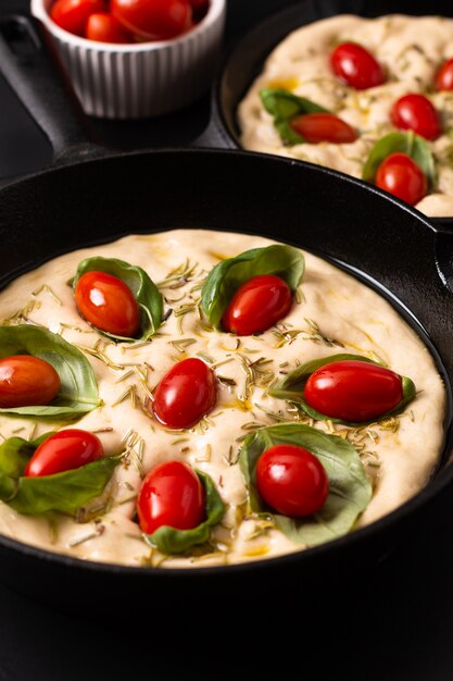 Focaccia bio fait maison dans une poêle en fonte sur fond noir avec espace de copie