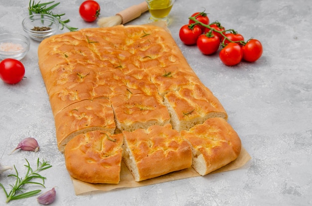 Focaccia italienne au sel de mer à l'ail et au romarin et à l'huile d'olive sur fond de béton gris