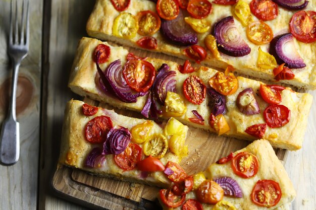 Focaccia maison fraîche avec oignons bleus et tomates cerises.