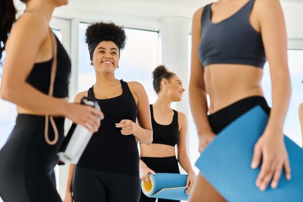 Focus sur une femme afro-américaine joyeuse qui regarde ses amis après un entraînement de pilates en studio.