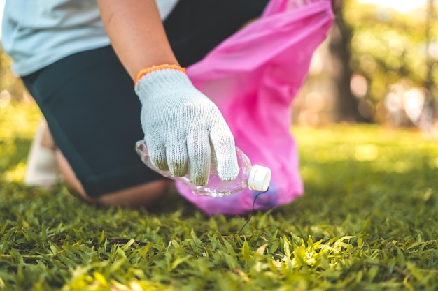 Focus Homme bénévole portant des gants ramassant des déchets de bouteilles sur la plage du parc Nettoyage de la nature