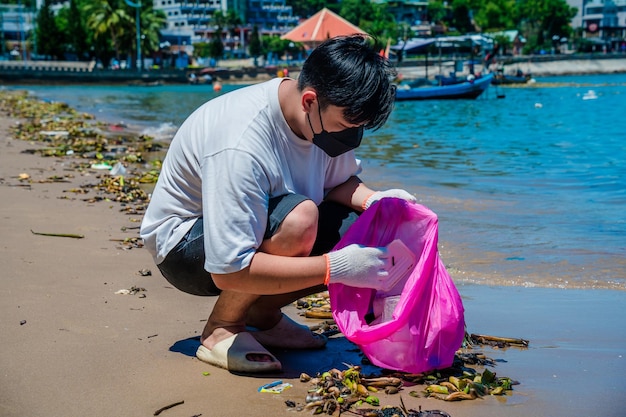 Focus Homme bénévole portant des gants ramassant des déchets de bouteilles sur la plage du parc Nettoyage de la nature