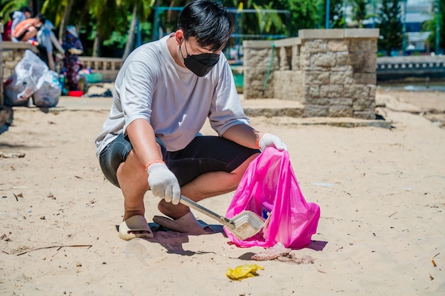 Focus Homme bénévole portant des gants ramassant des déchets de bouteilles sur la plage du parc Nettoyage de la nature