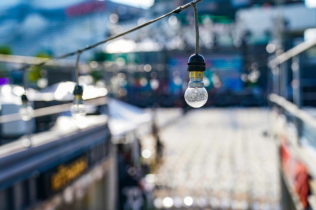 Focus sur la lampe suspendue cercle Vintage sur la ligne avec concert en plein air flou dans un fond de jour.