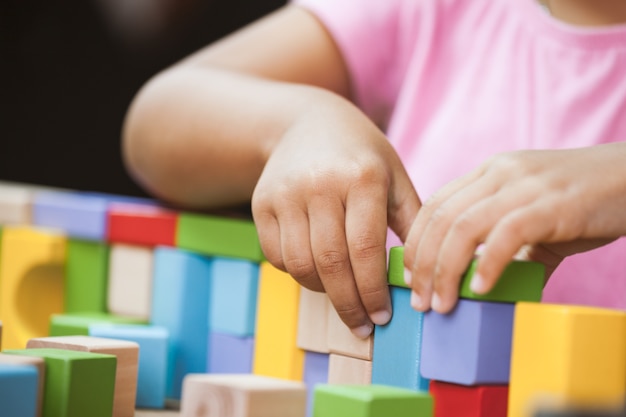 Focus sur la main de l&#39;enfant jouant avec des blocs de bois colorés dans le ton de couleur vintage