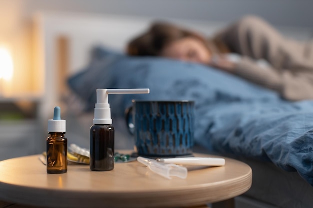 Focus sélectif sur divers médicaments et pilules pour le traitement de la grippe et du rhume. Sur l'arrière-plan flou fatigué femme endormie. Concept de soins de santé.