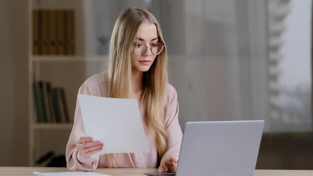 Focused étudiante femme d'affaires gestionnaire enseignant travailleur avec des lunettes dame blonde est assis