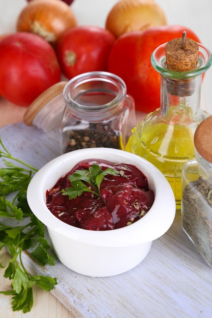 Foie cru dans un bol avec des épices et condiments sur close-up de table en bois