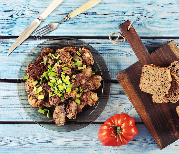 Photo foie frit avec oignons sur une assiette, tomates et pain de seigle