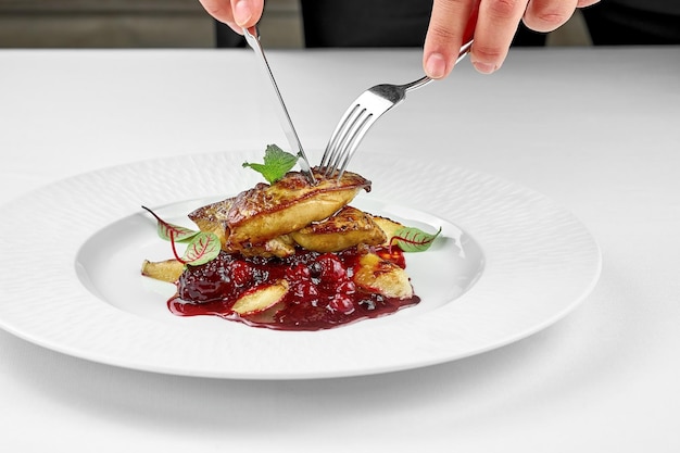 Foie gras avec sauce aux baies sur une assiette blanche sur une assiette blanche Gros plan Mise au point sélective