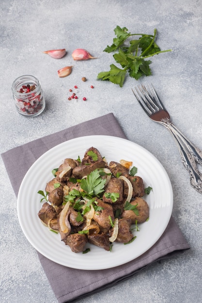 Foie de poulet au four avec oignons sur une assiette.