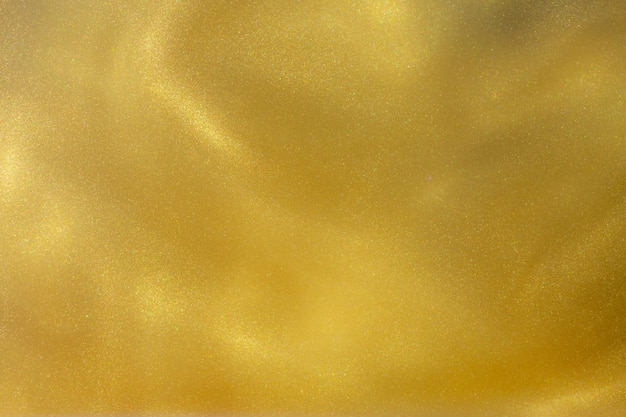 Fond abstrait brillant jaune doré peint des paillettes acryliques dans l'eau