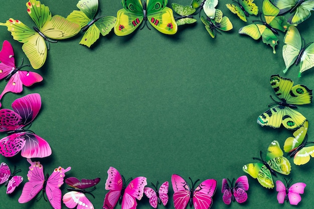 Fond abstrait couleur émeraude avec papillons artificiels verts et violets maquette avec copie