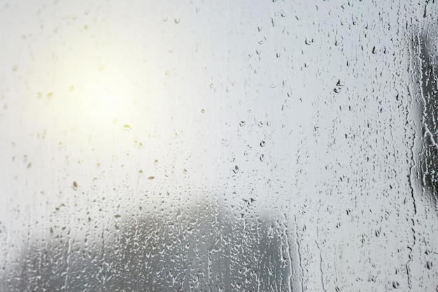 Fond abstrait avec des gouttes de pluie sur la fenêtre et la lumière du jour floue