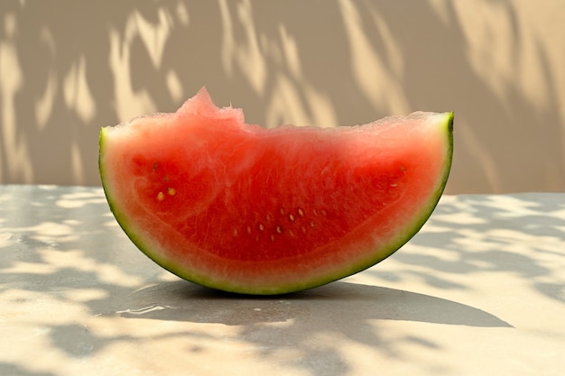 Fond d'aliments d'été. Tranche de pastèque mûre sur fond chaud avec des nuances dures et la lumière du soleil.