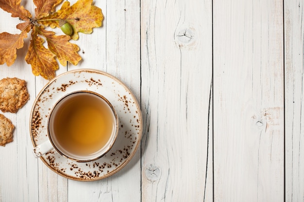 Fond d'automne avec des feuilles de chêne, une tasse de thé et des biscuits à l'avoine