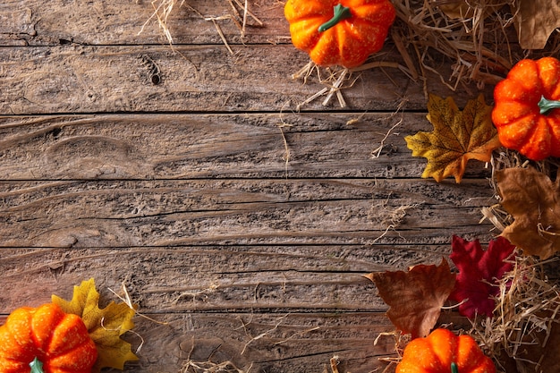 Fond d'automne avec des feuilles et des citrouilles sur fond de bois