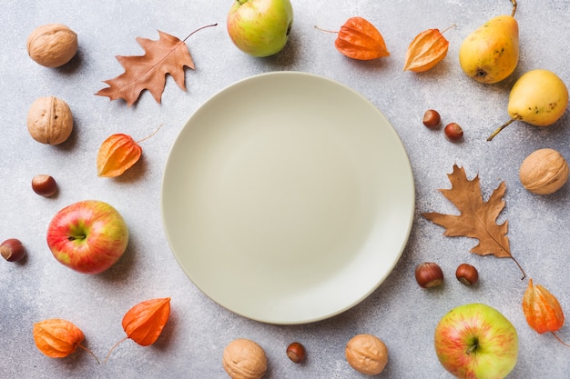 Fond d'automne avec les feuilles jaunes, pommes citrouilles poires et noix