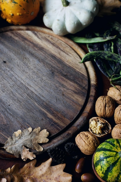 Fond d'automne avec des glands de citrouille décoratifs noix verts feuilles d'automne et planche de bois avec un espace pour le texte sur la table en pierre sombre récolte nature morte composition fond d'action de grâces