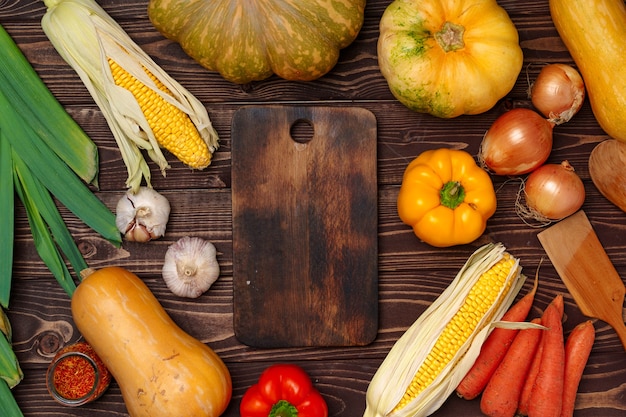 Fond d'automne avec des légumes frais et une planche à découper en bois