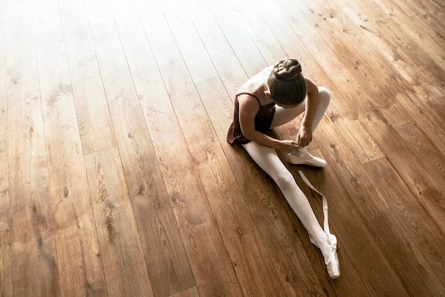 Fond de ballerine, jeune fille attachant des chaussures sur le plancher en bois