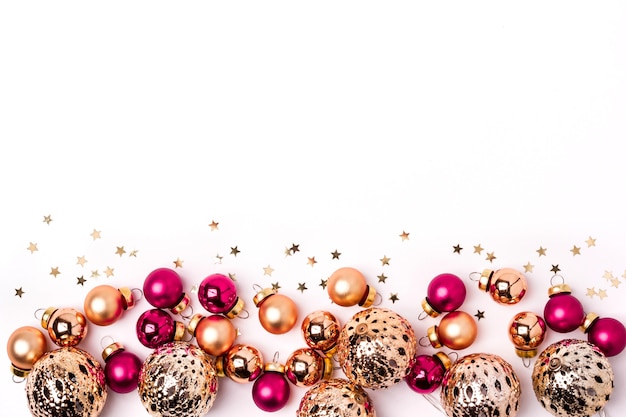 Fond blanc de Noël. Boules dorées et roses brillantes et bordure de confettis