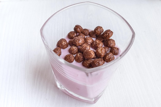 Fond blanc. Petit déjeuner léger. Yaourt avec boules de chocolat. Menu enfant. Collation utile.