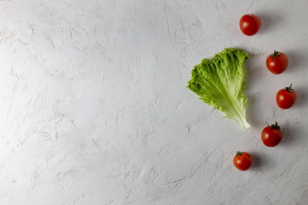 Sur un fond blanc se trouvent des tomates et de la laitue. Copiez l'espace.