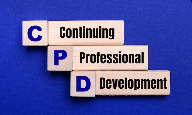 Sur un fond bleu clair, des blocs et des cubes en bois clair avec le texte CPD Continuing Professional Development