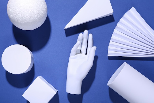 Fond bleu minimalisme avec des formes géométriques et des mains de mannequin Ombres à la mode