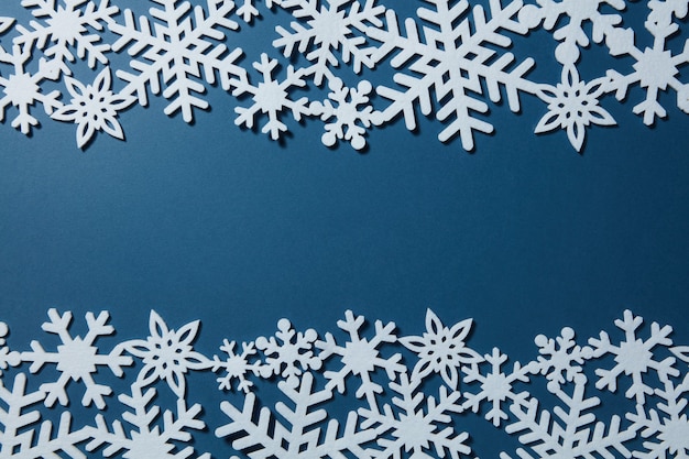 Fond bleu de Noël avec des flocons de neige blancs. Carte postale de Noël