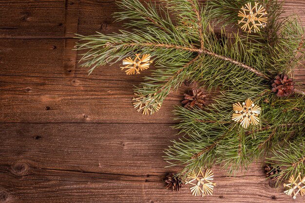 Fond en bois ancien festif de Noël. Concept de décoration de Noël zéro déchet. Branches de pin à feuilles persistantes fraîches et flocons de neige en paille, pose à plat