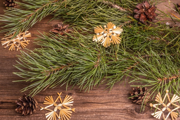 Fond en bois ancien festif de Noël. Concept de décoration de Noël zéro déchet. Branches de pin à feuilles persistantes fraîches et flocons de neige en paille, pose à plat