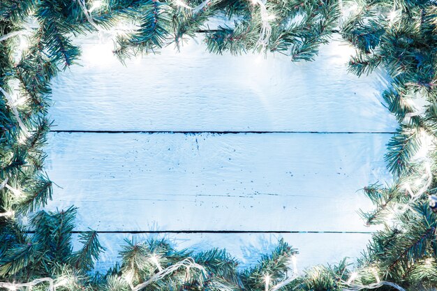 Fond en bois bleu clair de Noël avec des branches d'ampoule et d'épinette