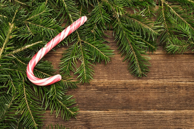 Fond en bois avec des bonbons de branches de sapin dans le coin du cadre