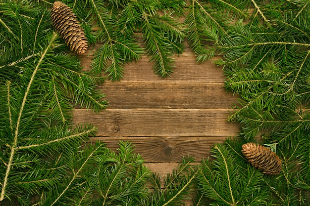 Fond en bois avec des branches de sapin et des cônes