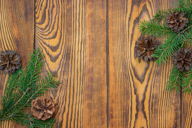 Fond en bois brun avec des branches de sapin et des cônes