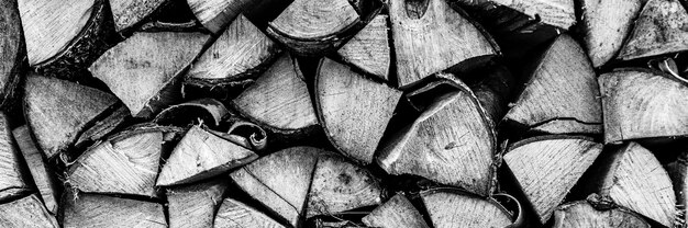 Photo fond de bois de chauffage texturé de bois haché pour allumer et chauffer la maison. un tas de bois avec du bois de chauffage empilé. la texture du bouleau. tonique en noir blanc ou gris. bannière