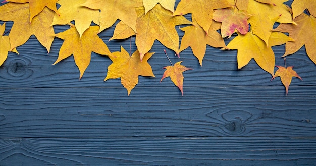 Fond en bois avec des feuilles d'érable jaunes d'automne Texture des feuilles et du bois Carte d'automne avec espace de copie