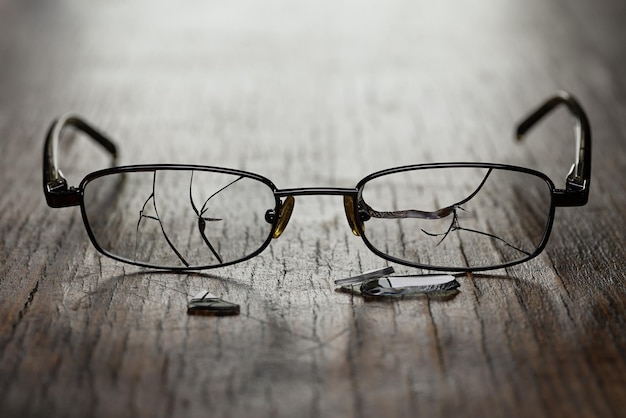 Photo sur un fond en bois fissuré, des lunettes pour hommes avec des verres fissurés et des fragments. photographie en studio