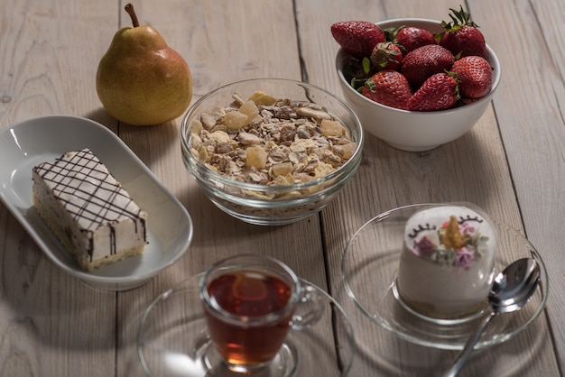 Sur Un Fond En Bois Un Gâteau Pour Enfants, Une Assiette Avec Des Fraises, Des Poires, Une Tasse De Thé