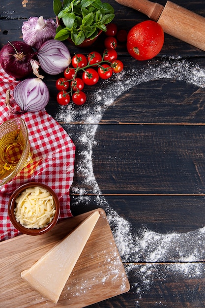 Fond en bois avec des ingrédients pour la pizza. Bois gris avec serviette à carreaux rouges. Espace de copie. Vue de dessus